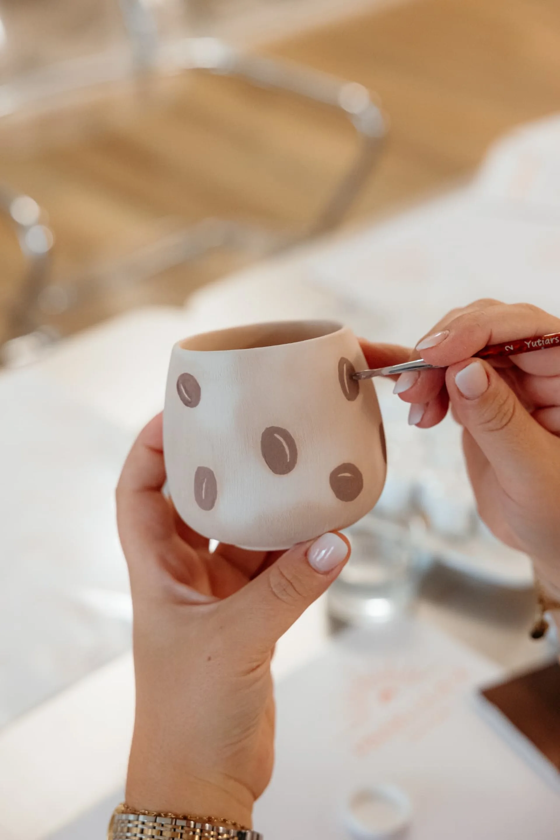 Hände bemalen einen Keramikbecher mit einem Kaffeebohnenmuster